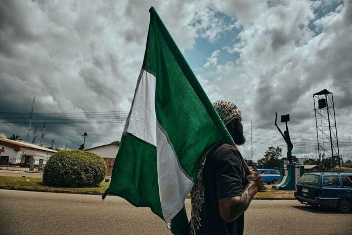 A protester holding the Nigerian flag walks the streets during demonstrations in a file photo. Date unknown. Photo via @Emmanuel Ikwuegbu/ACN.