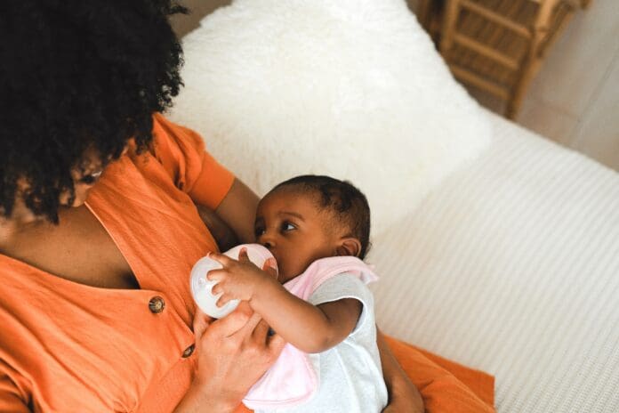 Baby fed by bottle. Photo via Pexels.