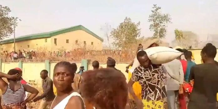 Looters in Abuja carry stolen bags of grain on Sunday, Feb. 3, 2024.