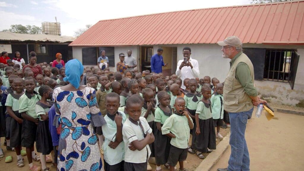Waiting to return to Borno. Some of the 320 kids at the Arise Academy in New Kunchingoro IDP camp in Abuja, getting a pep talk in November 2023 from Founder Mike Arnold. All the children were born of parents who fled attacks from Boko Haram on Gwoza in Borno State in 2014. Courtesy of Mike Arnold. 