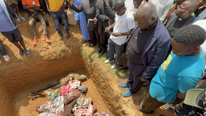 Pastor Ezekiel Dachomo, second from right, looks over the bodies of nine members of his extended family killed in a night attack on July 12 in Kum, near Jos.